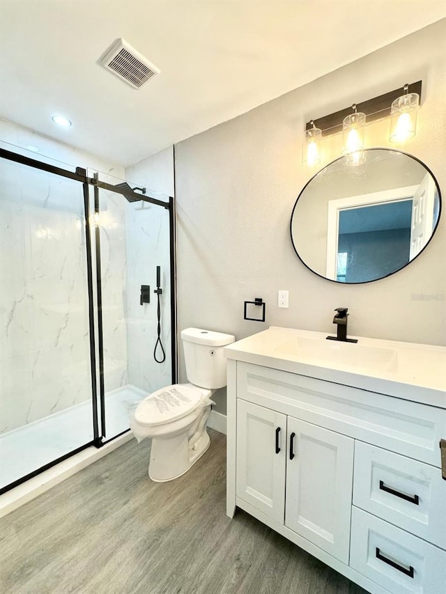 bathroom featuring hardwood / wood-style floors, vanity, toilet, and a shower with door