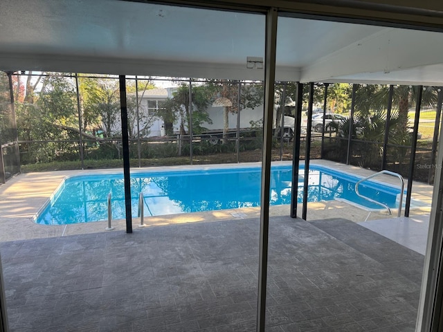 view of swimming pool featuring a patio and glass enclosure