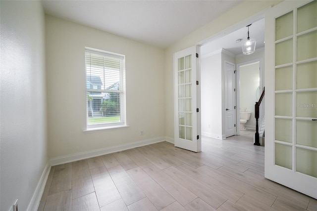 unfurnished room with french doors, ornamental molding, and light wood-type flooring