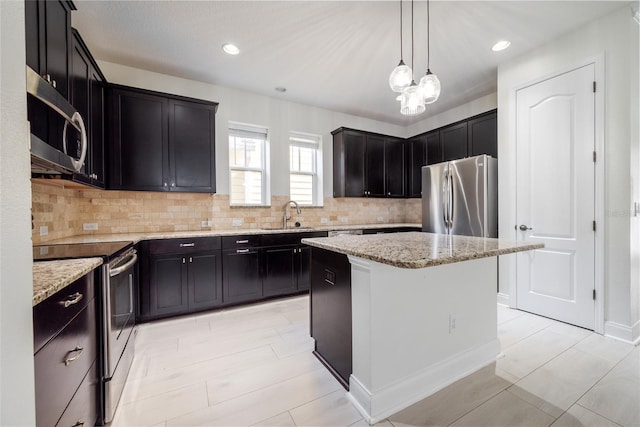 kitchen with light stone countertops, a center island, hanging light fixtures, stainless steel appliances, and backsplash