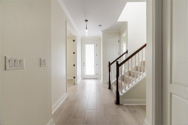 entryway featuring a textured ceiling, light hardwood / wood-style floors, and crown molding