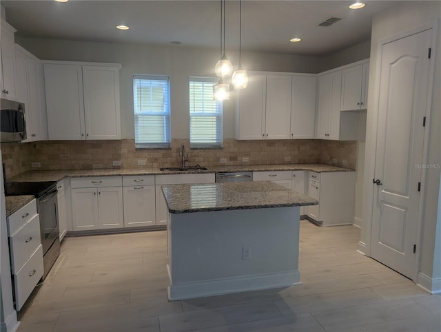 kitchen featuring light stone countertops, a sink, stainless steel appliances, tasteful backsplash, and visible vents