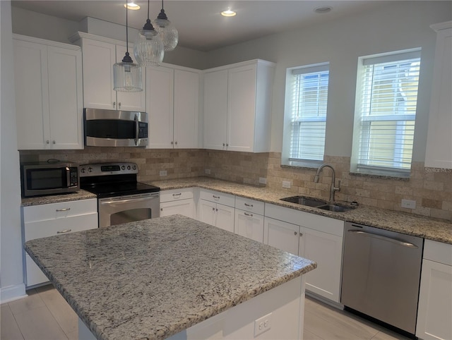 kitchen with backsplash, a center island, a sink, white cabinets, and stainless steel appliances