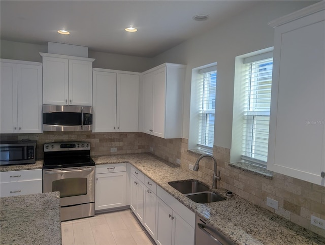 kitchen with a sink, white cabinetry, tasteful backsplash, and stainless steel appliances