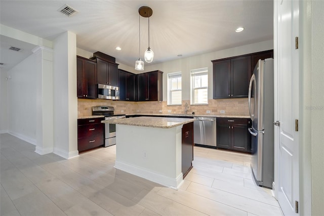 kitchen featuring appliances with stainless steel finishes, decorative backsplash, a center island, and visible vents