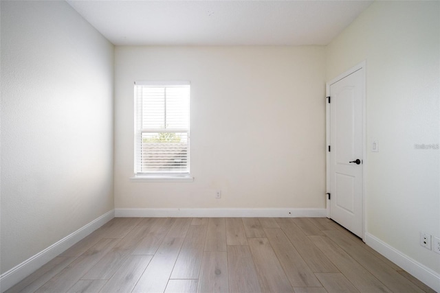 unfurnished room with baseboards and light wood finished floors