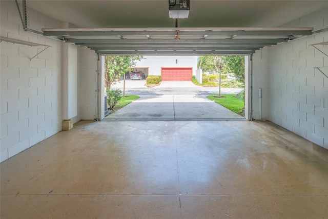 garage featuring concrete block wall and a garage door opener