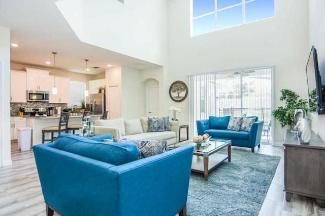 living room with light hardwood / wood-style flooring and a towering ceiling