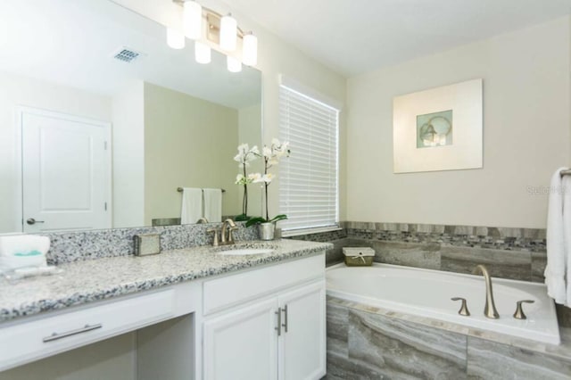 bathroom with vanity and a relaxing tiled tub