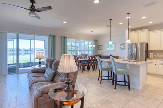 living room with light tile patterned floors, a wealth of natural light, ornamental molding, and ceiling fan