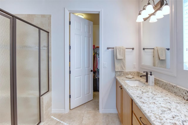 bathroom with tile patterned floors, vanity, a shower with shower door, and an inviting chandelier