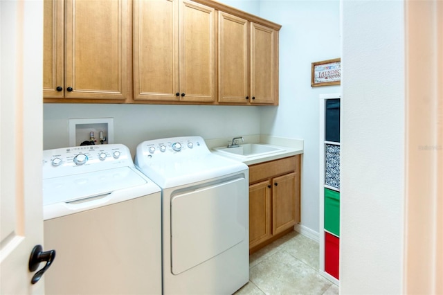 washroom featuring separate washer and dryer, sink, light tile patterned floors, and cabinets