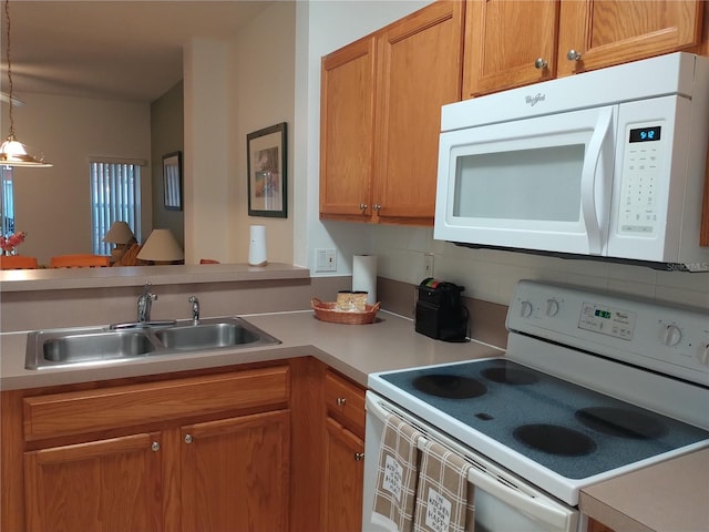 kitchen with backsplash, white appliances, sink, and hanging light fixtures