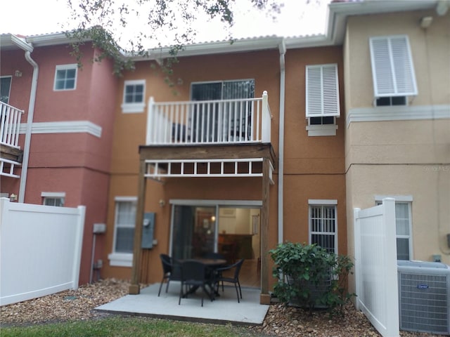 back of house featuring cooling unit, a balcony, and a patio