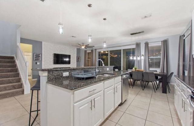 kitchen featuring stainless steel dishwasher, decorative light fixtures, sink, and an island with sink