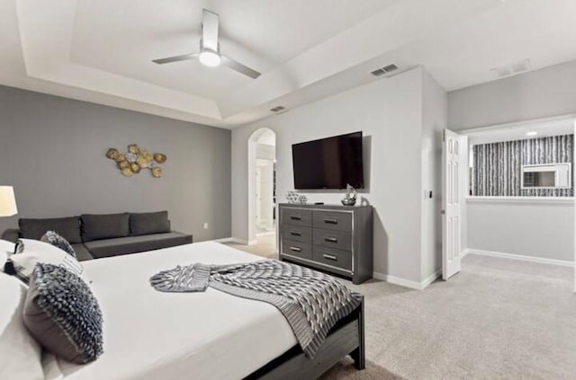 carpeted bedroom featuring a tray ceiling and ceiling fan