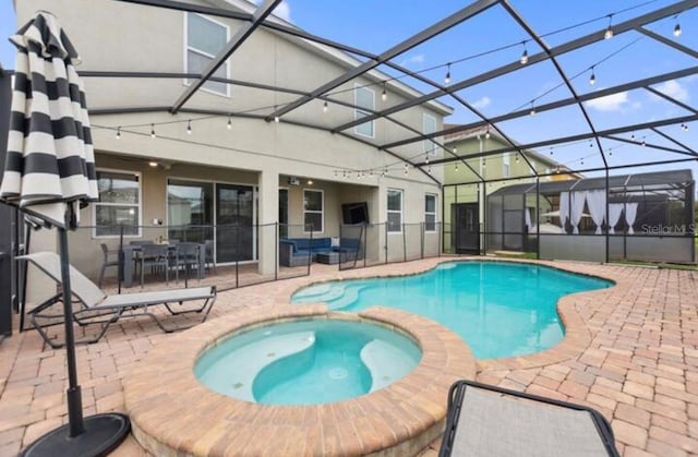 view of swimming pool with an in ground hot tub, glass enclosure, and a patio area