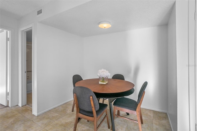 tiled dining space with a textured ceiling