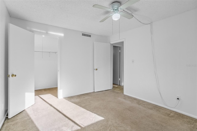 unfurnished bedroom featuring ceiling fan, a textured ceiling, light carpet, and a closet