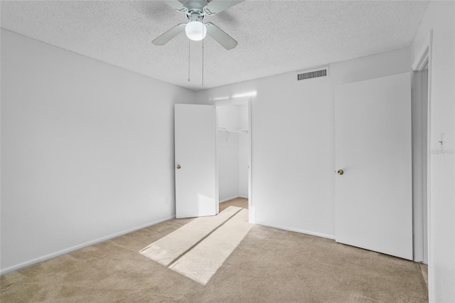 unfurnished bedroom with ceiling fan, a textured ceiling, and light carpet