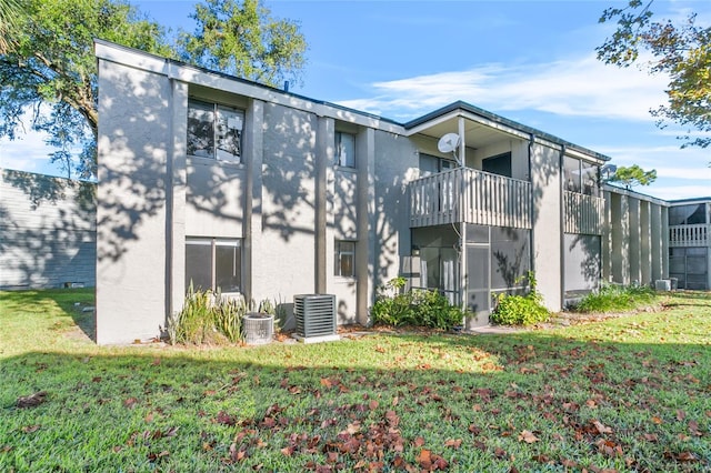 rear view of house featuring a yard, a balcony, and central AC unit