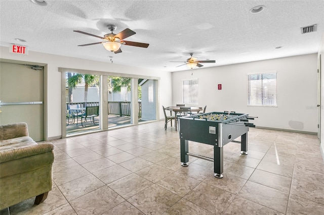 game room featuring ceiling fan, light tile patterned floors, and a textured ceiling