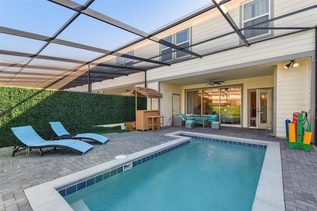 view of swimming pool with an outdoor hangout area, ceiling fan, a lanai, a patio area, and a bar