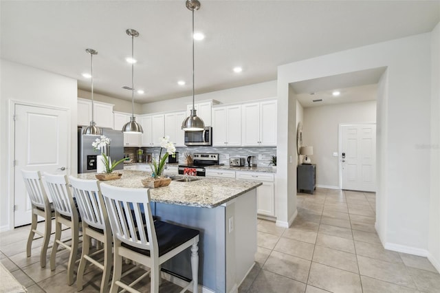 kitchen featuring backsplash, white cabinets, hanging light fixtures, and appliances with stainless steel finishes