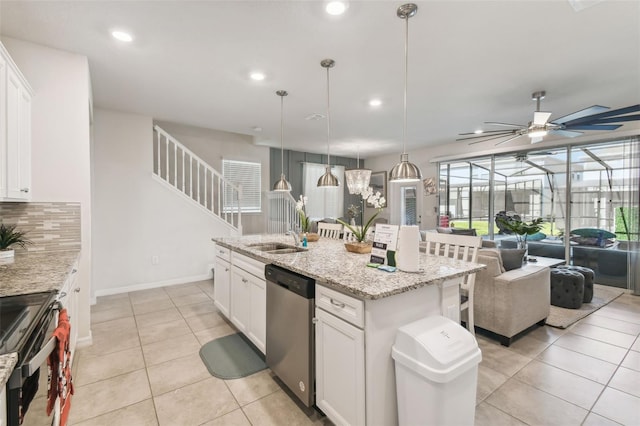 kitchen featuring sink, an island with sink, appliances with stainless steel finishes, decorative light fixtures, and white cabinetry