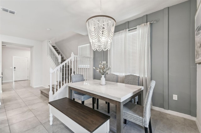 dining space featuring light tile patterned flooring and a notable chandelier