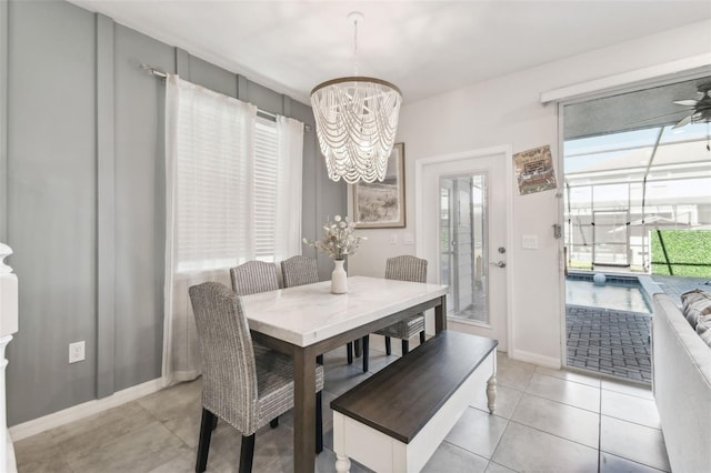 tiled dining space with ceiling fan with notable chandelier