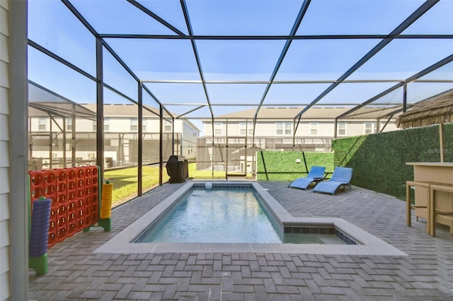 view of pool featuring a patio, glass enclosure, and a hot tub