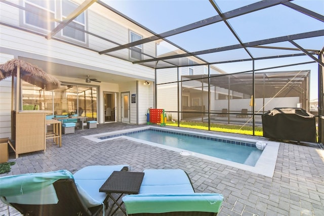 view of swimming pool featuring glass enclosure, a grill, a patio, and ceiling fan