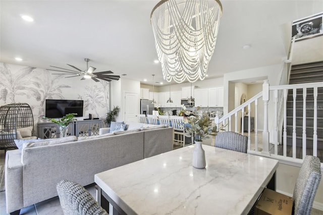 tiled dining space with ceiling fan with notable chandelier