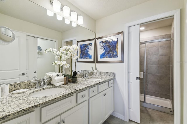 bathroom with a shower with door, vanity, a textured ceiling, and tile patterned flooring