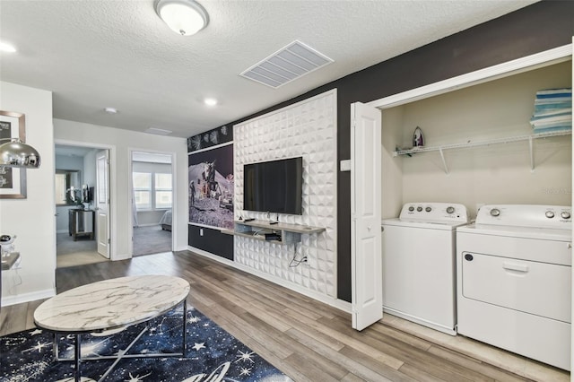 clothes washing area with hardwood / wood-style flooring, washer and clothes dryer, and a textured ceiling