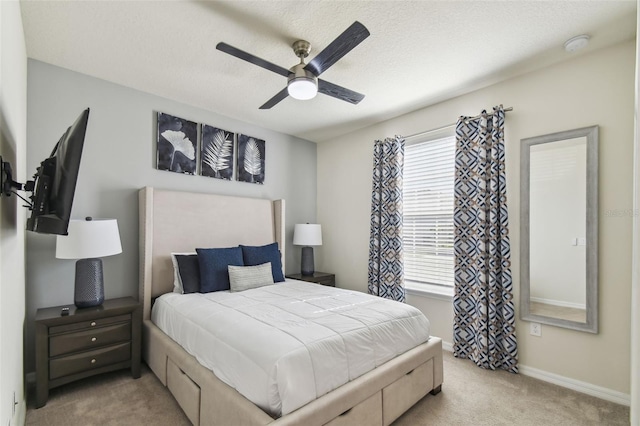 bedroom with ceiling fan, light colored carpet, and a textured ceiling