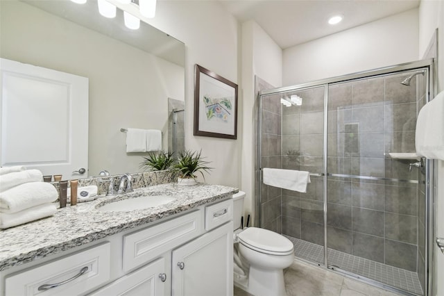 bathroom featuring tile patterned flooring, vanity, toilet, and a shower with door