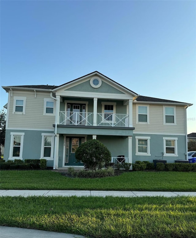 view of front of house with a balcony and a front lawn