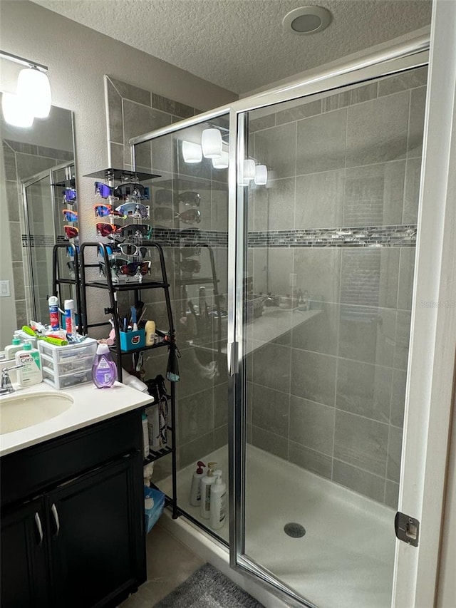 bathroom with vanity, a shower with door, and a textured ceiling