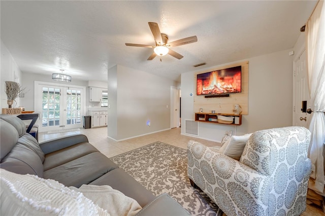 living room with ceiling fan, light tile patterned flooring, a textured ceiling, and french doors