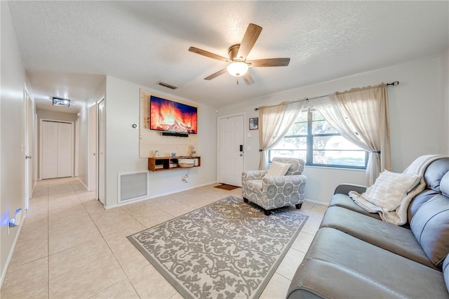 living room with ceiling fan, light tile patterned flooring, and a textured ceiling