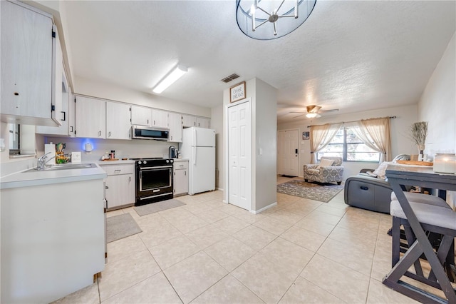 kitchen featuring black electric range oven, white cabinets, white refrigerator, sink, and a textured ceiling