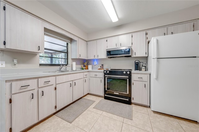 kitchen with sink, black range with electric cooktop, white fridge, a textured ceiling, and light tile patterned flooring