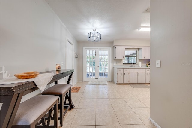 tiled dining room with french doors, a textured ceiling, and sink