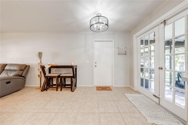 entrance foyer featuring light tile patterned floors, an inviting chandelier, french doors, and a healthy amount of sunlight