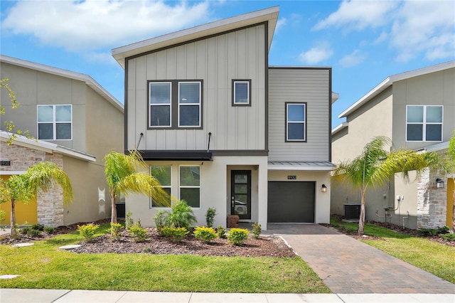 8932 Cabot Cliffs Dr, Davenport, FL 33896 - view of front of house with cooling unit, board and batten siding, a standing seam roof, driveway, and an attached garage