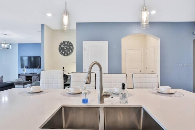 8932 Cabot Cliffs Dr, Davenport, FL 33896 - kitchen with a sink, decorative light fixtures, arched walkways, open floor plan, and light countertops