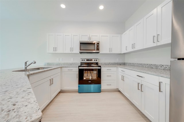 kitchen with white cabinets, stainless steel appliances, light stone countertops, and sink