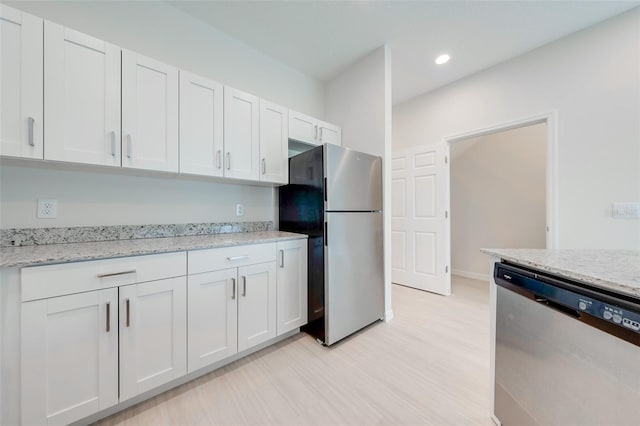 kitchen with light stone countertops, appliances with stainless steel finishes, light wood-type flooring, and white cabinetry